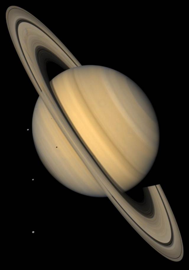 Aproximação da Voyager 2 a Saturno mostrando seus anéis e três de seus satélites na escuridão:  Tethys, Dione e Rhea.